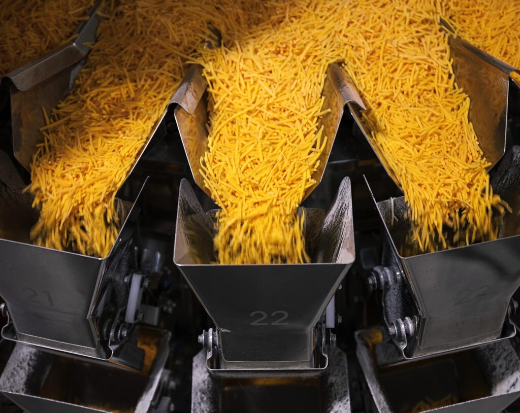 Shredded cheese being distributed during production