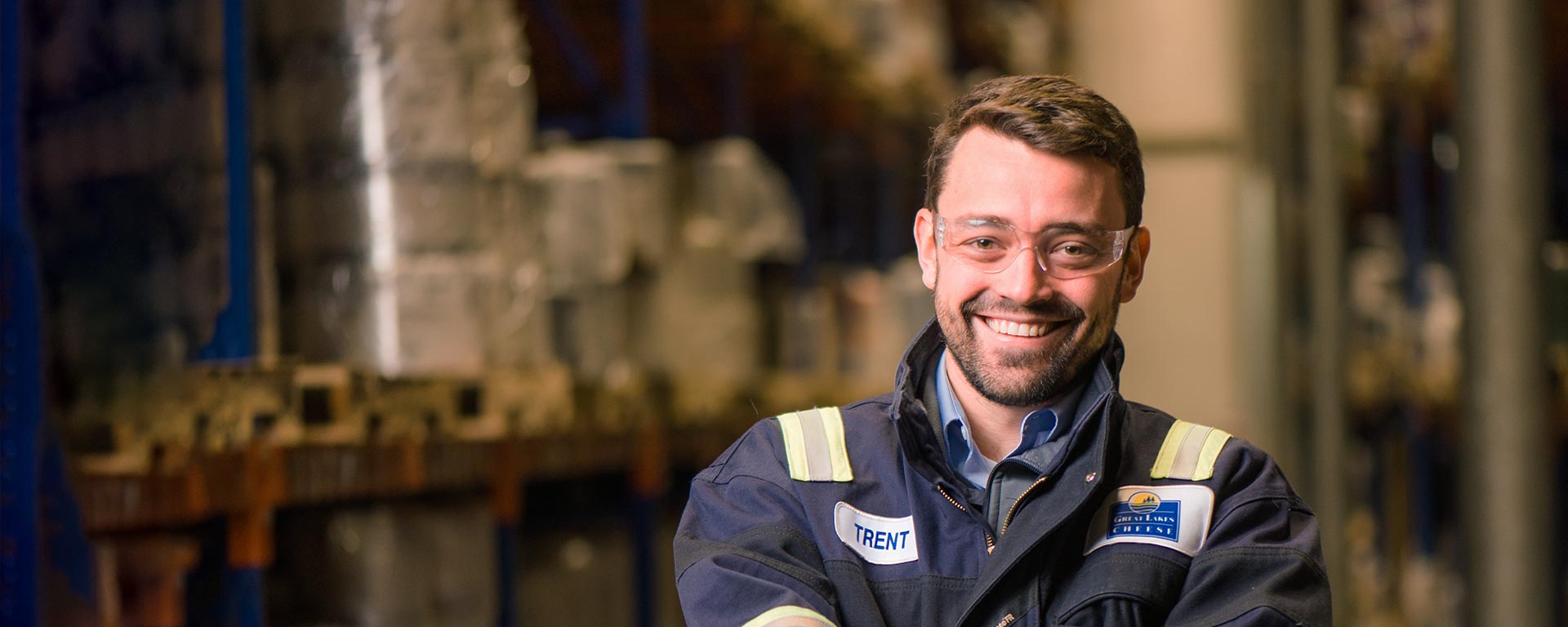 A smiling factory employee with his arms crossed